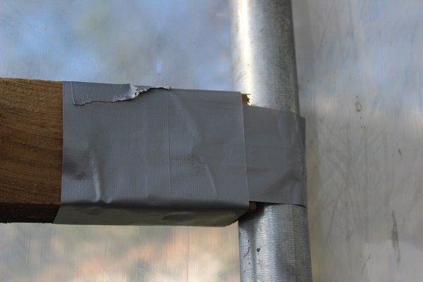 Duct tape covering perforated metal strips connecting a batten to a metal frame with greenhouse foil over the outside
